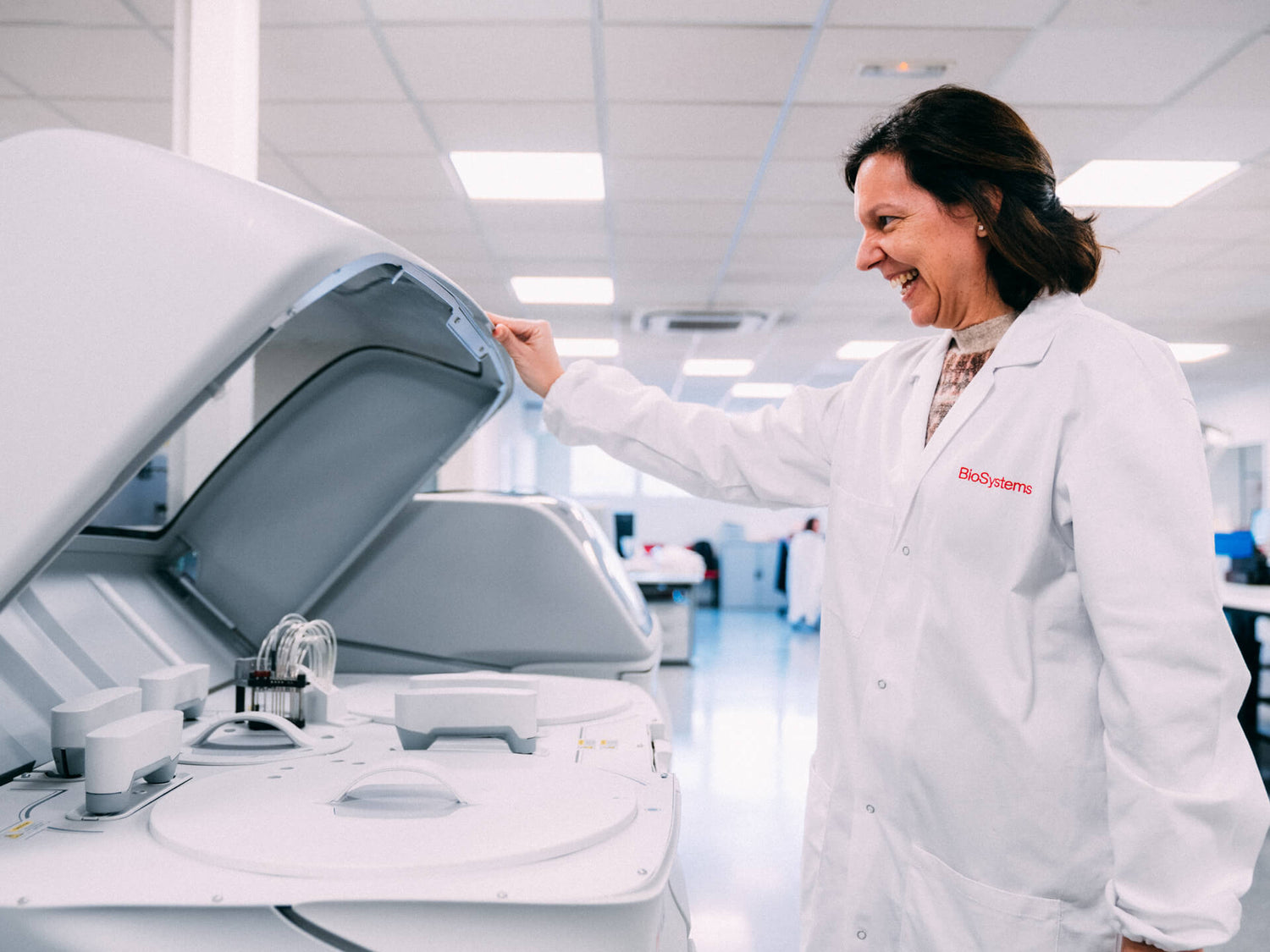 Person in a lab coat interacting with medical equipment in a clinical setting