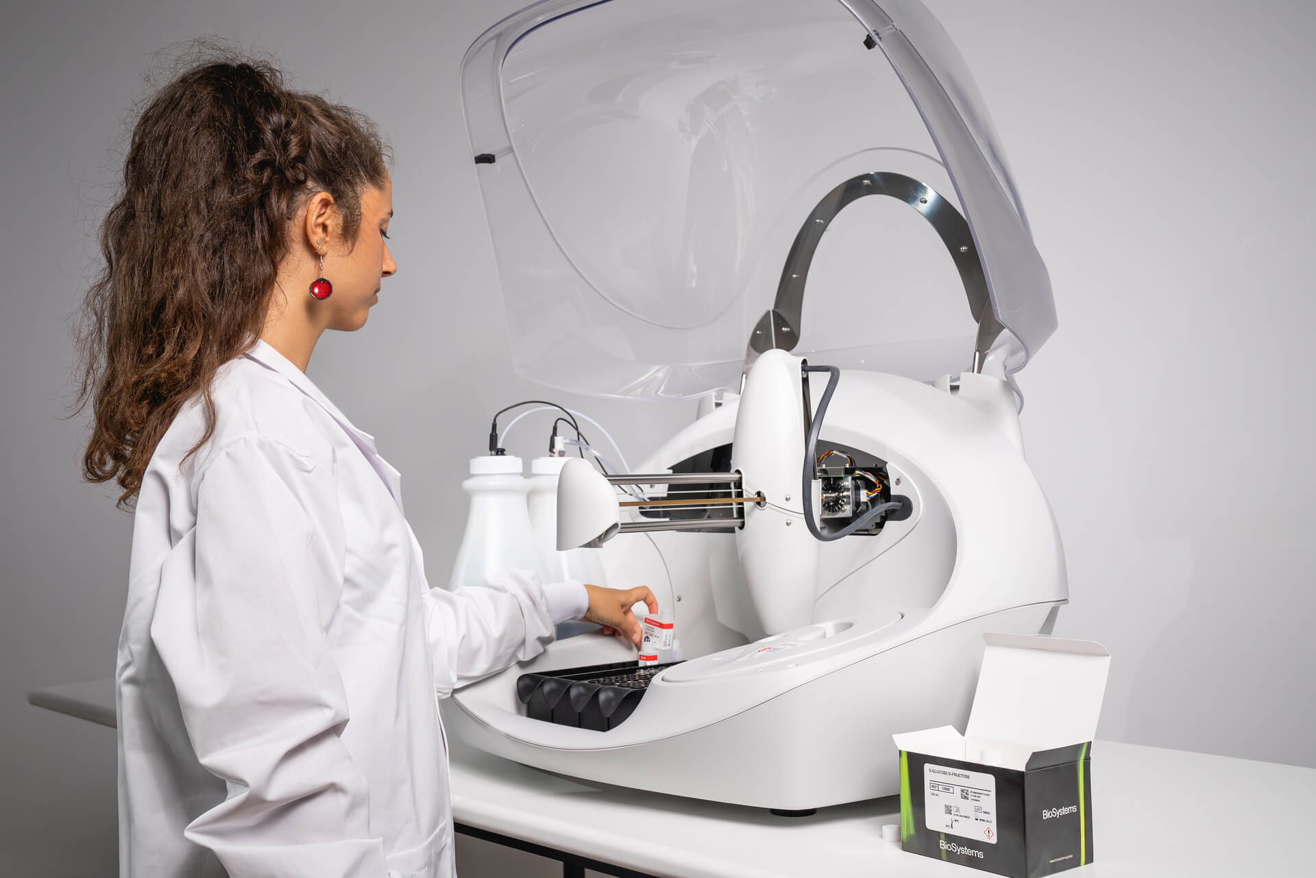Person in a lab coat interacting with a large machine in a laboratory setting