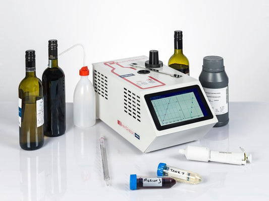 An image displaying a compact laboratory instrument, EasyCheck, with a digital screen, alongside various wine bottles, a bottle cap, and test tubes, indicating its use for wine stability analysis.