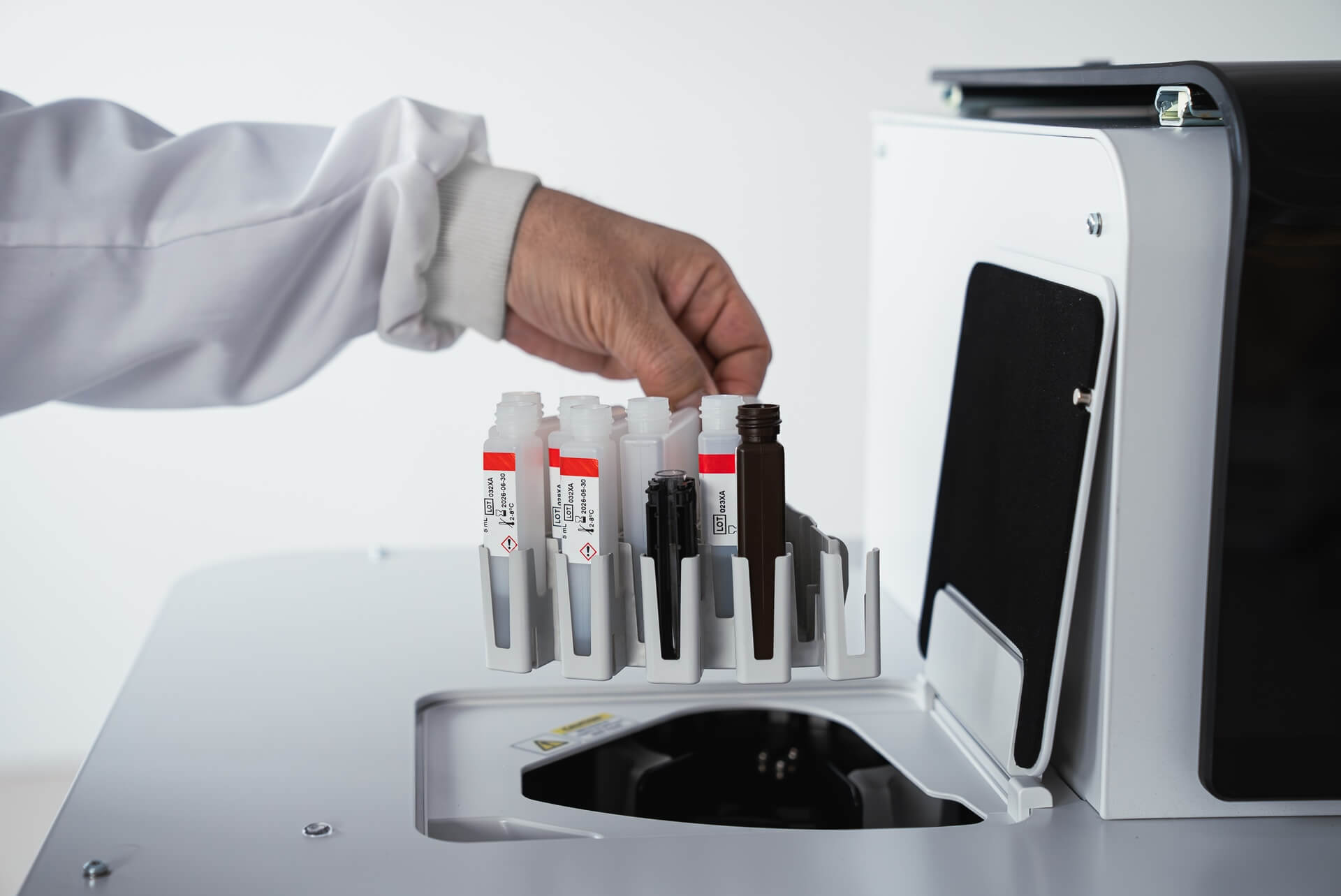 Person placing test tubes into a laboratory machine.