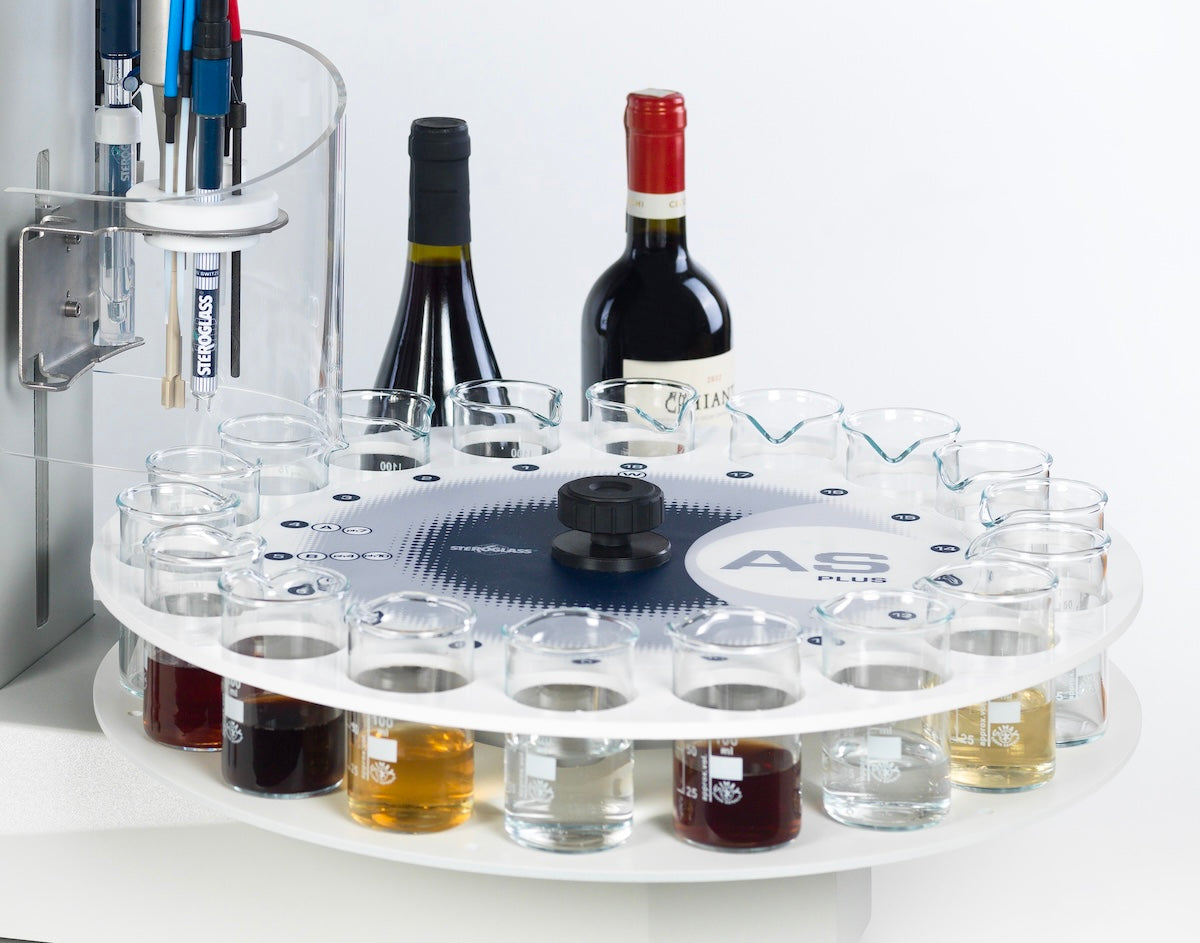 Wine tasting setup with a rotary tasting tray and bottles of wine on a white background